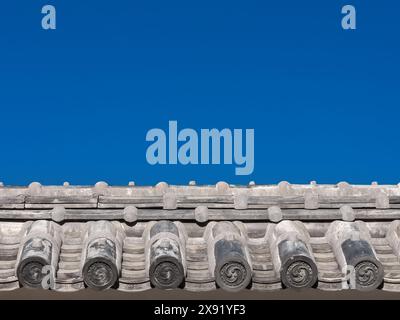 Japanese traditional grey roof tile with old spiral motif and blue sky above as background (with copy space) Stock Photo