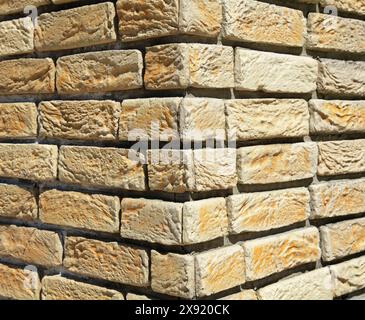 Curved texture and background of brick wall. Structural masonry surface. Corner of a wall or building. Beige-component background. Textured coating Stock Photo