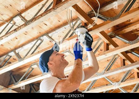 An Electrician Male Working on basement bulb Stock Photo