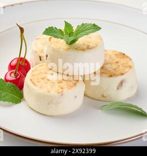 Round small fried cheesecakes on a plate. Background white Stock Photo