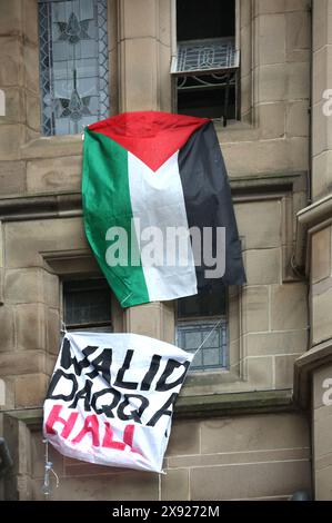 Students occupying and barricaded in Whitworth Hall renamed the building ‘Walid Daqqa Hall and a Palestinian flag flies from upper windows during a protest. Students and supporters occupy Brunswick Park now renamed by them as Dr Adnan Al-Bursh Park and Whitworth Hall at Manchester University. Protesters demand that the University Stop arming Israel and end their complicity in genocide. They insist that the University end their partnership with arms manufacturer BAE Systems, end their ties with Tel Aviv and Hebrew Universities in Israel and adopt a policy of ensuring all research is ethical and Stock Photo