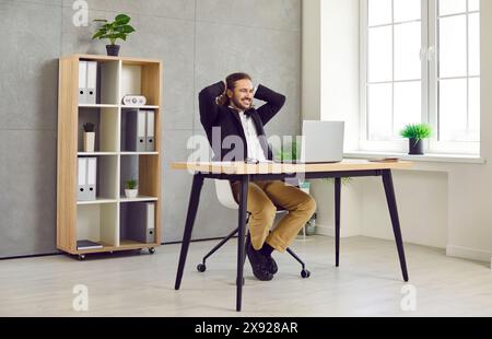 Young confident business man working on a laptop at office looking on computer screen. Stock Photo