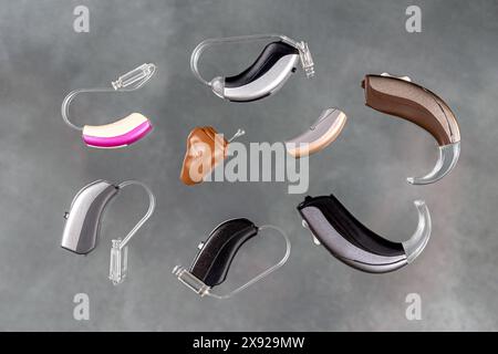 Presentation of a wide range of hearing aids seen from above on a gray background. Hearing disorders-Hearing aids 016561 033 Stock Photo