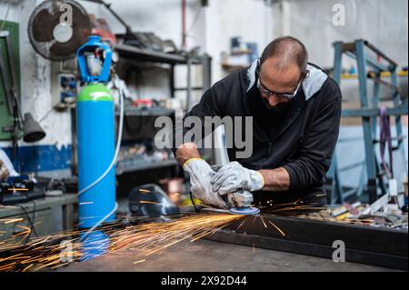 Using the flexible disc grinder on a metal bar: When the tool touches the surface, numerous orange sparks are projected. Concept of metal processing i Stock Photo