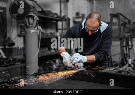 Using the flexible disc grinder on a metal bar: When the tool touches the surface, numerous orange sparks are projected. Concept of metal processing i Stock Photo