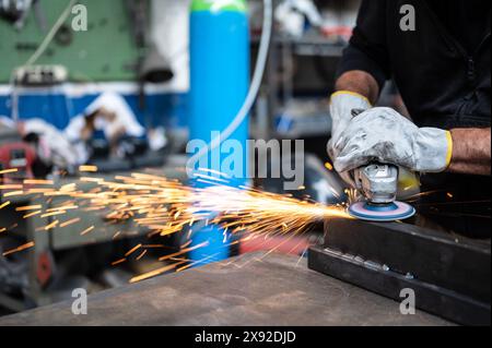 Using the flexible disc grinder on a metal bar: When the tool touches the surface, numerous orange sparks are projected. Concept of metal processing i Stock Photo