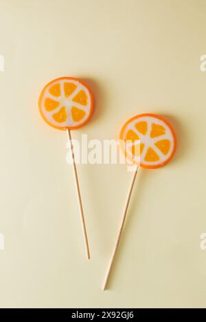 Two orange lollipops on beige background. Minimal concept idea Stock Photo