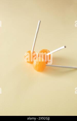 Three orange lollipops on beige background. Minimal concept idea Stock Photo