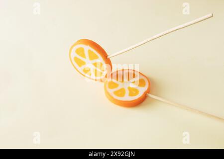 Two orange lollipops on beige background. Minimal concept idea Stock Photo