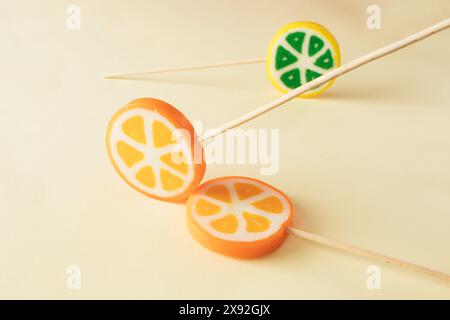 Three orange and green lollipops on beige background. Minimal concept idea Stock Photo