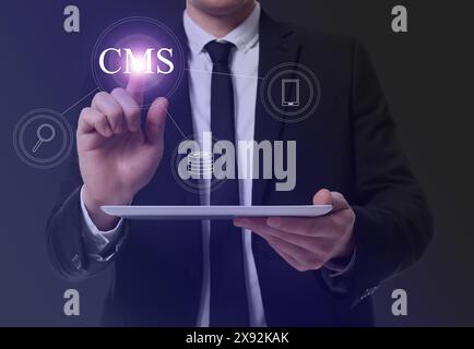 CMS. Man with tablet using virtual screen, closeup. Scheme with icons on dark background Stock Photo