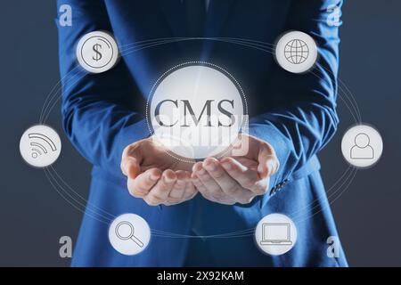 CMS. Man using virtual screen, closeup. Scheme with icons on dark background Stock Photo