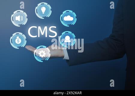 CMS. Man using virtual screen, closeup. Scheme with icons on blue background Stock Photo