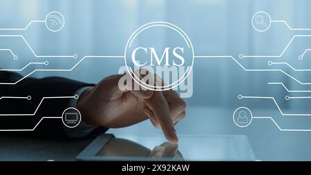 CMS. Man using tablet at table, closeup. Scheme with icons over device Stock Photo