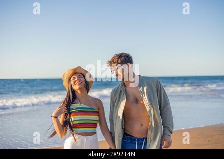multicultural Latina couple gazes affectionately into each other's eyes while enjoying the summer sunset on the beach shore. Their love is palpable am Stock Photo