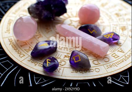 Scandinavian runes made of amethyst and rose quartz crystals on a board with symbols of the zodiac signs. Predictions, witchcraft, spiritual esoteric Stock Photo