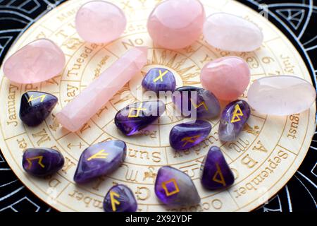 Scandinavian runes made of amethyst and rose quartz crystals on a board with symbols of the zodiac signs. Predictions, witchcraft, spiritual esoteric Stock Photo