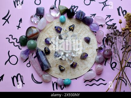 Scandinavian runes made of amethyst and dry herbs on a pink background with a board with symbols of the zodiac signs. Predictions, witchcraft, spiritu Stock Photo