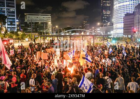 Tel Aviv, Israel. 25th May, 2024. Protestors gather around a bonfire as they wave the Israeli flag on Kaplan junction during the demonstration. Tens of thousands of Israelis demonstrated with the hostages families against Prime Minister Benjamin Netanyahu in Tel Aviv, demanding an immediate hostage deal and general elections. Clashes with the Israeli police occurred when protestors did set up bonfires at Kaplan junction. (Credit Image: © Matan Golan/SOPA Images via ZUMA Press Wire) EDITORIAL USAGE ONLY! Not for Commercial USAGE! Stock Photo