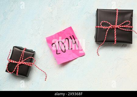 Sticky note with year 2024 and gift boxes on gradient background Stock Photo