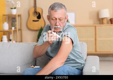Senior man giving himself insulin injection at home. Diabetes concept Stock Photo