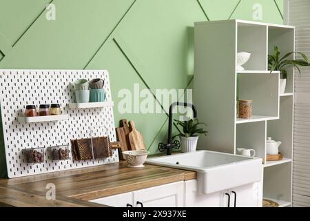 Pegboard, white counters and rack near green wall in interior of modern ...