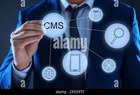 CMS. Man using virtual screen, closeup. Scheme with icons on dark background Stock Photo