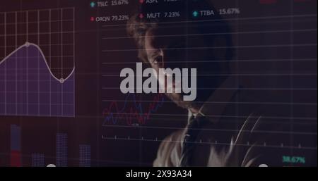 Caucasian young man analyzing financial graphs on transparent screen Stock Photo