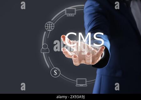 CMS. Man using virtual screen, closeup. Scheme with icons on dark background Stock Photo