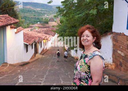 Hispanic woman traveler smiling, strolling through the colonial streets of the most beautiful town in Colombia, Barichara. Stock Photo