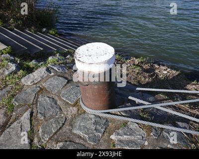 Nautical mooring bollard with lines attached near steps going into water Stock Photo