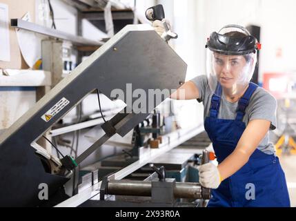 Female machinist operating industrial profile cutting machine Stock Photo