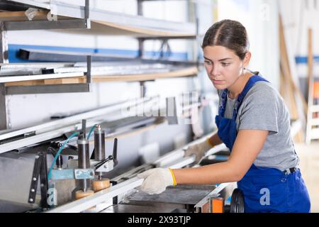 Female machinist operating industrial profile cutting machine Stock Photo
