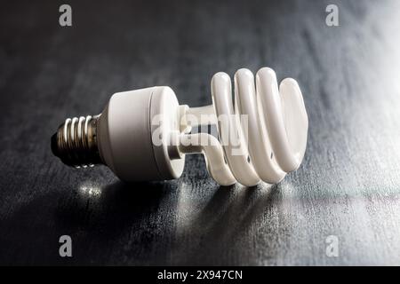 Energy saving light bulb on a black table. Fluorescent Lightbulb Stock Photo