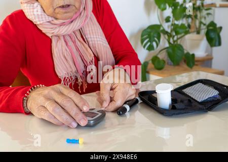 Patient with diabetes handling a domestic kit to check sugar on blood levels at home Stock Photo