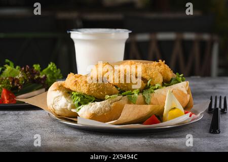Deep fried squid in bread with greens on the side. Squid sandwich Stock Photo