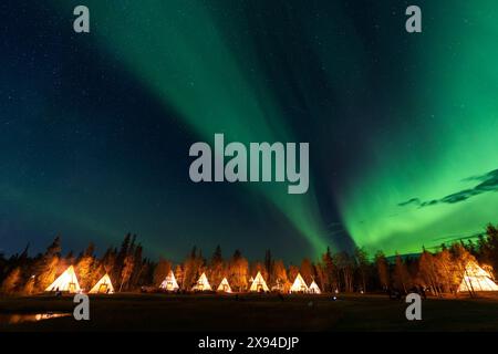 Amazing northern lights dancing over the light up Tipi or Tepees at Aurora Village in Yellowknife, Northwest Territories, Canada. Stock Photo