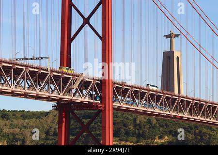 Twin decks of Lisbon’s April 25th Anniversary bridge, two motor coaches traverse to upper deck, while a Fertagus commuter train runs on the lower deck. Stock Photo