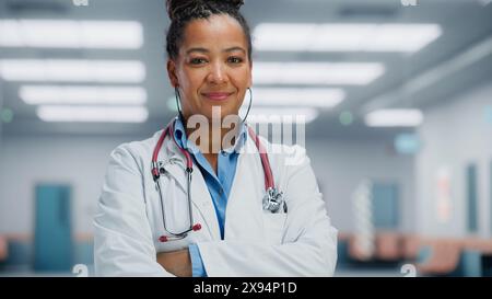 Medical Hospital Medium Portrait: African American Female Medical Doctor Takes of Glasses Looks Sincerely at Camera and Smiles. Successful Health Care Physician in White Lab Coat Ready to Save Lives Stock Photo