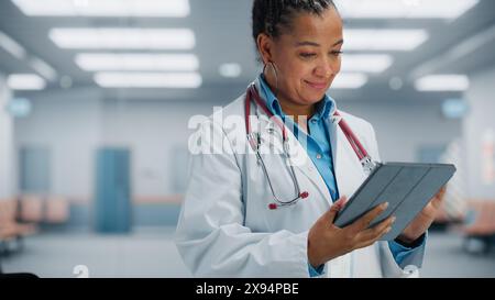 Medical Hospital Portrait: Confident African American Female Medical Doctor Using Digital Tablet Computer. Health Care Black Physician in White Lab Coat Prescribes Medicine, Ready to Save Lives Stock Photo