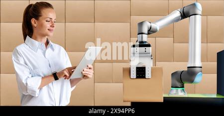 Modern businesswoman operates robotic arm in logistic centre remotely using her digital tablet. Stock Photo