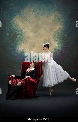 Ballerina in flowing white gown leaning towards her partner dreaming in chair. Dancers in scene of famous performance against vintage style background Stock Photo