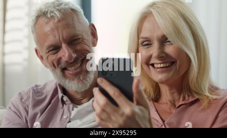 Happy Caucasian couple elderly senior mature wife husband surfing on Internet communicating social network choosing goods online man woman laugh Stock Photo