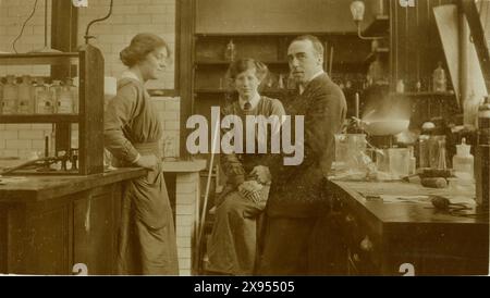 Original, interesting and rare pre WW1 era postcard of college women in a science lab, bunsen burner heating up ceramic crucible, with an older man, possibly the professor, circa 1912 from hairstyles of girls. Victorian women. Edwardian women.  Female scientist.  U.K. Stock Photo