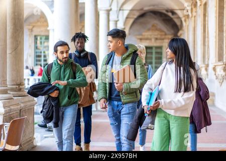 A diverse group of university students walking together on campus, engaging in conversation and carrying books. The image captures the vibrancy and mu Stock Photo