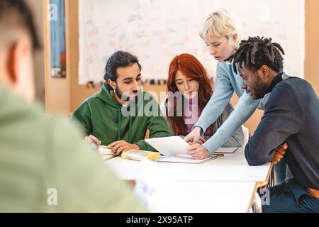 Group of diverse college students working together on a project in a classroom setting - Teamwork, diversity, and collaboration, with students engaged Stock Photo
