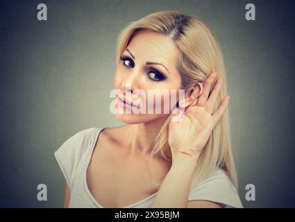 Woman holds her hand near ear and listens carefully Stock Photo