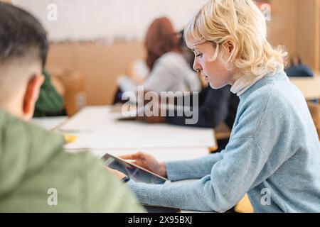 Focused college student studying with a tablet in a classroom - Concentration, modern education, and academic engagement, with the student deeply invo Stock Photo