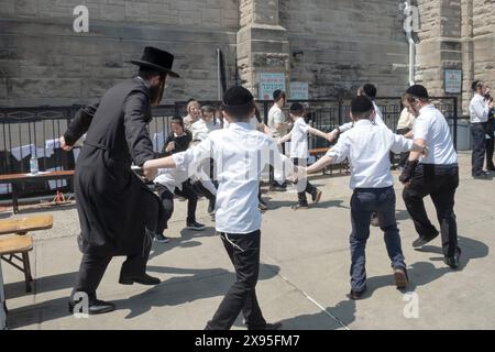 At a Lag B'Omer celebration in Brooklyn, a Lively rabbi dances with his young male students. In Williamsburg, 2024. Stock Photo