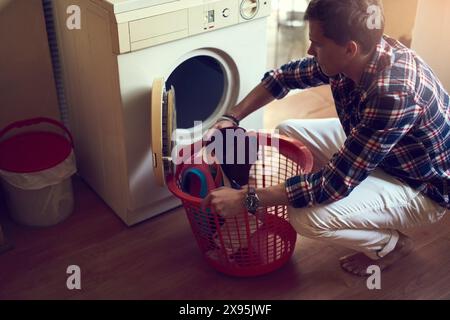 House, washing machine and man with basket for laundry, spring cleaning and loading in washer and clothes. Home, guy and person in apartment Stock Photo